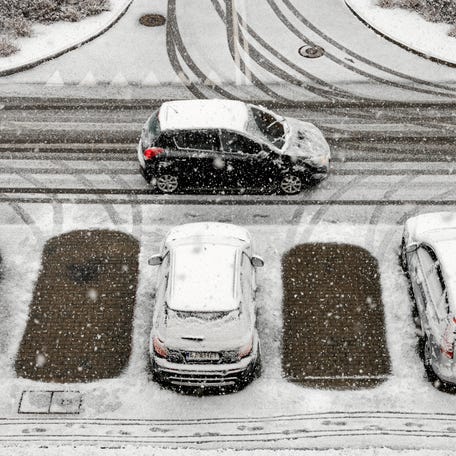 A car drives past snow-covered cars parked in a car park after snowfall in Rzeszow, Poland, November 21, 2025. Agencja Wyborcza.pl/Patryk Ogorzalek via REUTERS ATTENTION EDITORS - THIS IMAGE WAS PROVIDED BY A THIRD PARTY. POLAND OUT.
