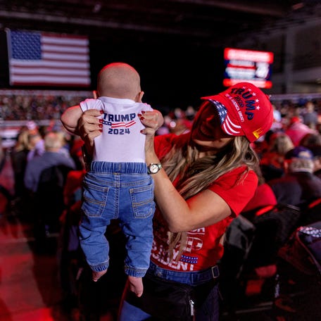 A woman holds her baby Fede Blanco as they wait for the start of a campaign rally of Republican presidential nominee and former U.S. President Donald Trump in Novi, Michigan, U.S., October 26, 2024.
