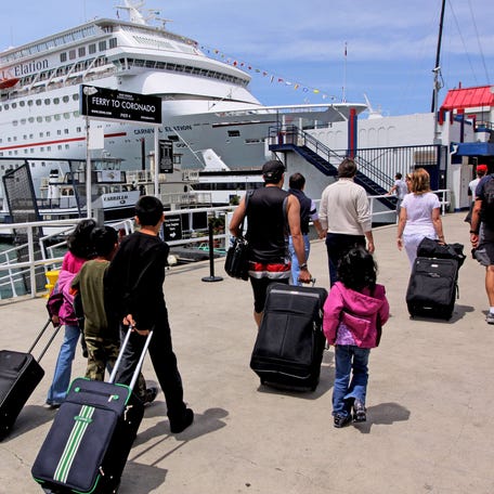 Cruise ship passengers walk with their suitcases before boarding at the San Diego Cruise Ship Terminal, May 3, 2009, in San Diego, California.
