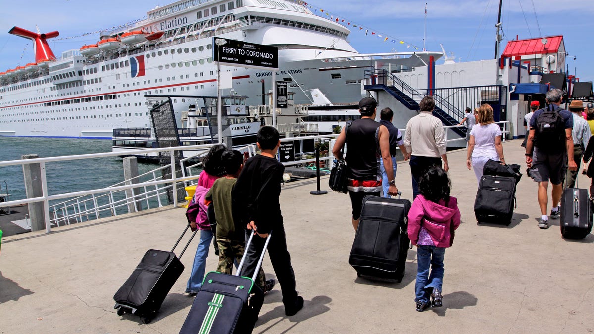 Cruise ship passengers walk with their suitcases before boarding at the San Diego Cruise Ship Terminal, May 3, 2009, in San Diego, California.