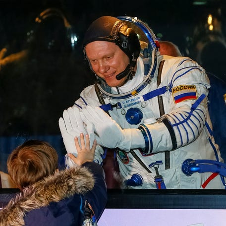 International Space Station (ISS) crew member Oleg Artemyev of Russia waves to his son from a bus on March 21, 2018 shortly before leaving to board a spacecraft at the Baikonur Cosmodrome, Kazakhstan.