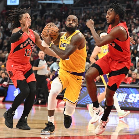 Los Angeles Lakers forward LeBron James (23) drives to the basket between Toronto Raptors guard Immanuel Quickley (5) and forward Collin Murray-Boyles (12) in the first half at Scotiabank Arena.