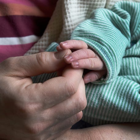 2019: Natalie Bruck touches the small fingers of her newborn baby boy Standish who was born April 6, 2019. â€œMy children are a blessing,â€ said Natalie. Photograph taken April 10, 2019 for a Mothers Day special feature.