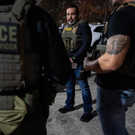 ICE officer John, left, listens to 11-year U.S. Immigration and Customs Enforcement veteran Keone Feliciano as they prepare to leave for the apprehension of a migrant without documentation in Kansas City, Mo., Nov. 18, 2025.
