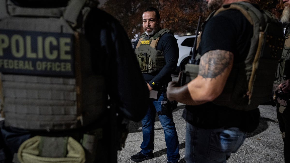 ICE officer John, left, listens to 11-year U.S. Immigration and Customs Enforcement veteran Keone Feliciano as they prepare to leave for the apprehension of a migrant without documentation in Kansas City, Mo., Nov. 18, 2025.