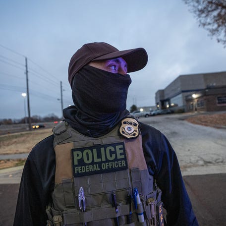 ICE officer John monitors a scene where ICE detained a Venezuelan migrant who had been under surveillance for days prior to the arrest in Kansas City, Mo., Nov. 18, 2025.