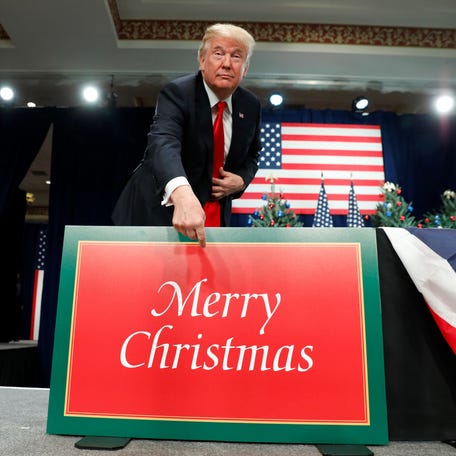 U.S. President Donald Trump points to a "Merry Christmas" placard on the stage as he arrives to deliver remarks on tax reform in St. Louis, Missouri, U.S. November 29, 2017. REUTERS/Kevin Lamarque