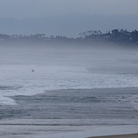 A swimmer makes their way out of the ocean as a winter storm approaches the coast in Del Mar, California, U.S., Nov. 14, 2025.