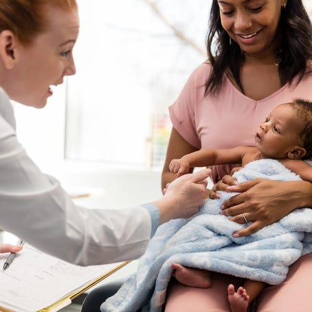 Doctor examining a newborn baby during a wellness check in the office.