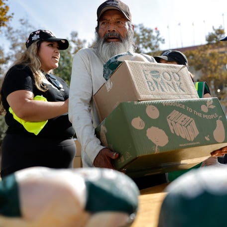 A recipient carries away food boxes at a large-scale food distribution in Exposition Park, in response to the federal government shutdown and SNAP/CalFresh food benefits delays, on November 11, 2025 in Los Angeles, California. The event was hosted by the Los Angeles Regional Food Bank and the office of L.A. County Supervisor Holly Mitchell.