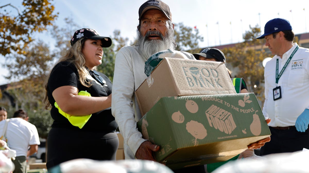 A recipient carries away food boxes at a large-scale food distribution in Exposition Park, in response to the federal government shutdown and SNAP/CalFresh food benefits delays, on November 11, 2025 in Los Angeles, California. The event was hosted by the Los Angeles Regional Food Bank and the office of L.A. County Supervisor Holly Mitchell.