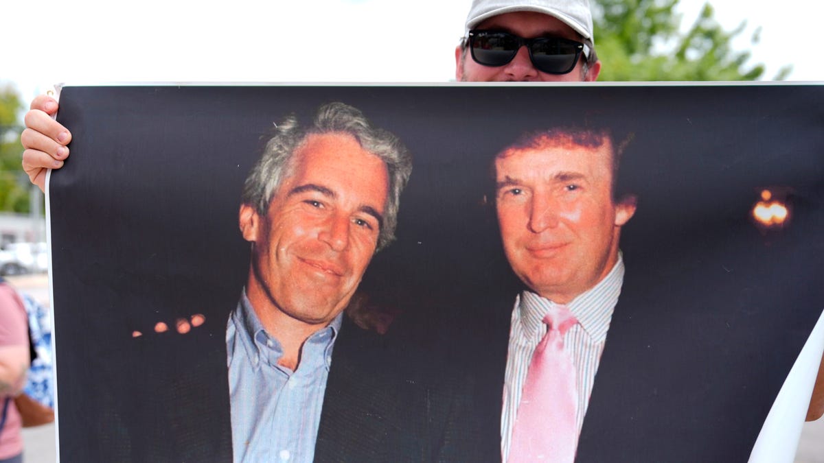 A protester holds up a photo of the future President Donald Trump with financier Jeffrey Epstein at a rally in Augusta, Georgia, on Aug. 2, 2025. Epstein, a convicted sex offender, died in a New York jail cell in 2019 while awaiting a federal sex trafficking trial.