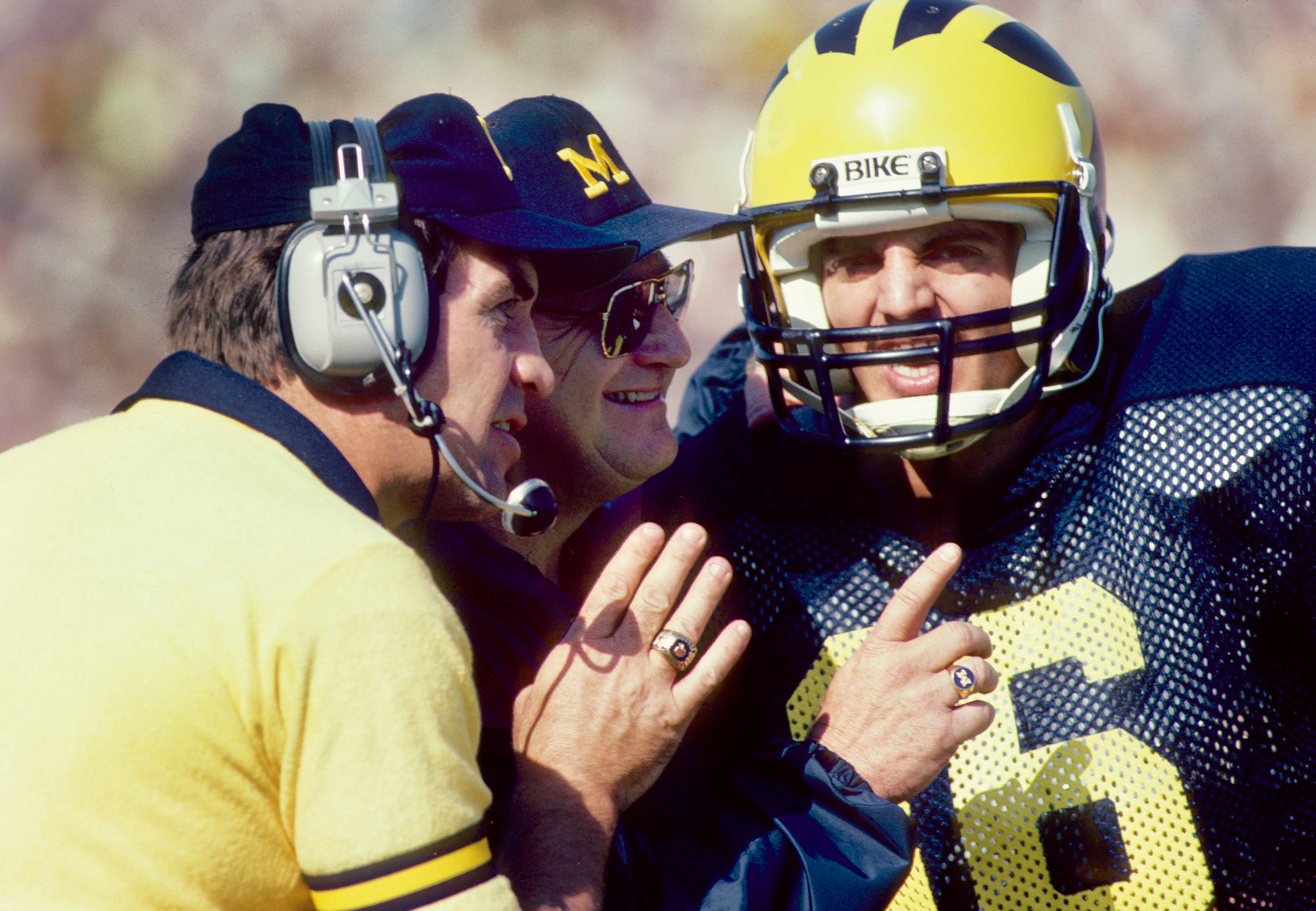 Michigan Wolverines head coach Bo Schembechler talks to quarterback Steve Smith alongside assistant coach Gary Moeller.