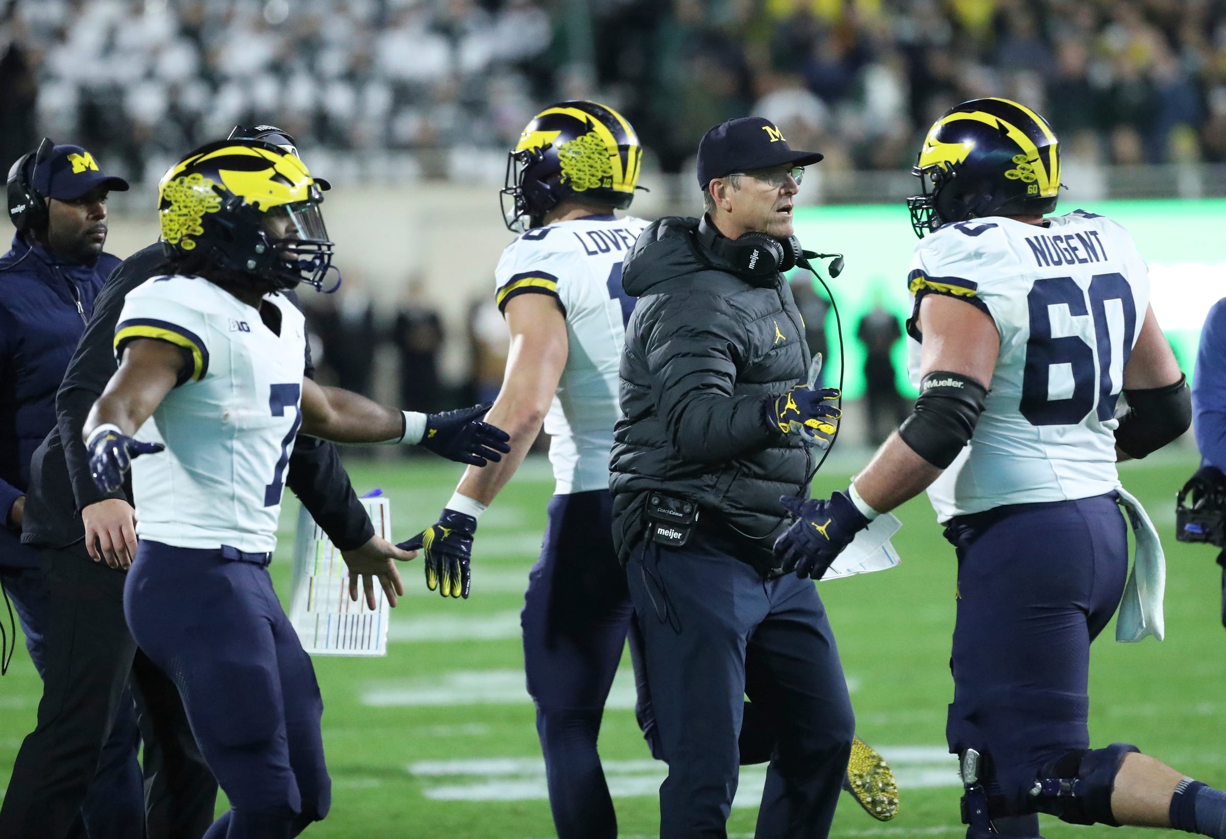 Michigan Wolverines head coach Jim Harbaugh high-fives players after a touchdown against the Michigan State Spartans.
