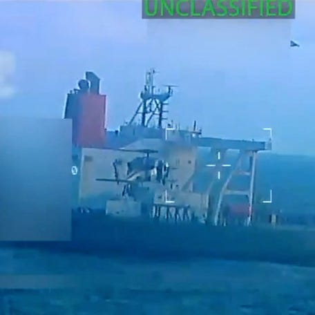 A U.S. military helicopter flies near an oil tanker during a raid described by U.S. Attorney General Pam Bondi as its seizure by the United States off the coast of Venezuela, Dec. 10, 2025, in a still image from video.
