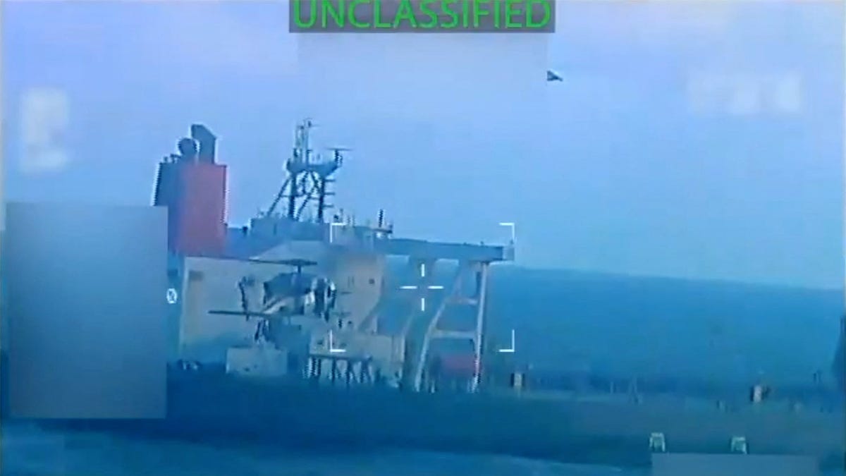 A U.S. military helicopter flies near an oil tanker during a raid described by U.S. Attorney General Pam Bondi as its seizure by the United States off the coast of Venezuela, Dec. 10, 2025, in a still image from video.