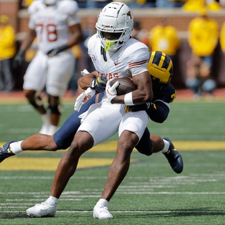 Texas running back Quintrevion Wisner (26) is tackled by a Michigan defender during their 2024 game at Michigan Stadium.