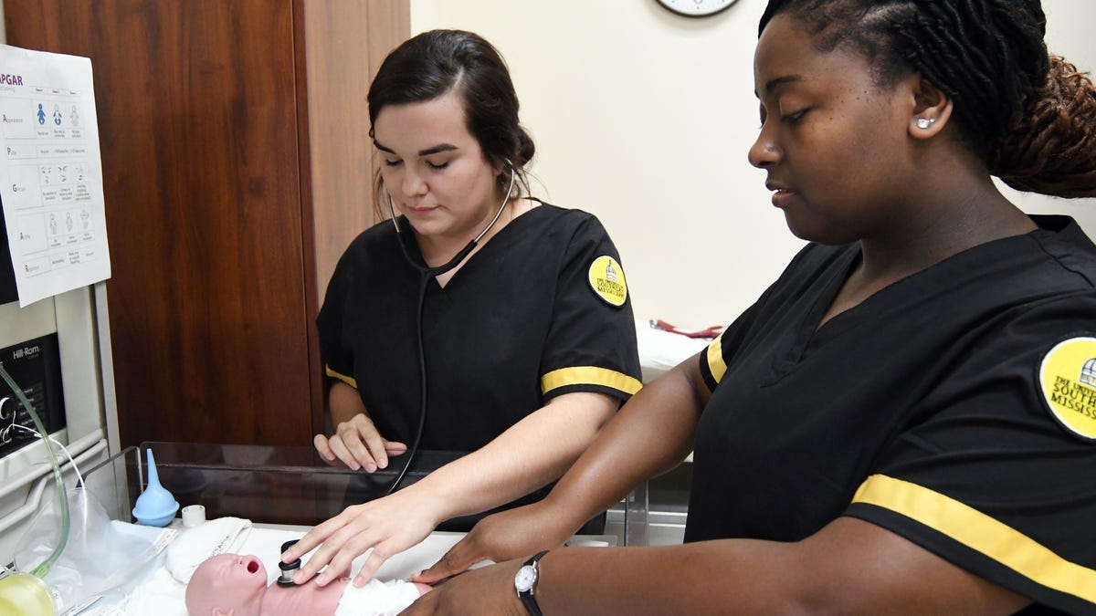 First year nursing students Tori Hopkins, left, and Takishia Lee, right, practice an examination in Southern Miss' nursing program. Takisha Lee knew there was a nursing shortage in Mississippi when she chose the profession, but says she got into the field to help people.               Usm College Of Nursing 1