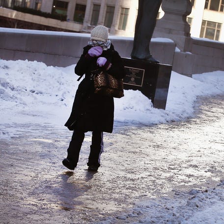 A pedestrian navigates an ice-covered sidewalk along the Chicago River as temperatures drop below zero January 27, 2014, in Chicago, Illinois.