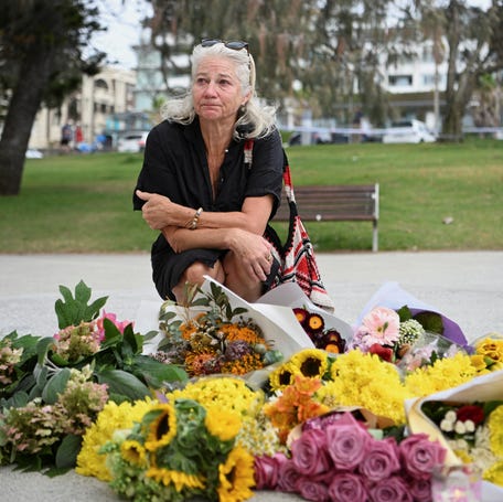 A woman reacts as flowers lie on the ground in a makeshift memorial following the attack on a Jewish holiday celebration at Sydney's Bondi Beach, in Sydney, Australia, December 15, 2025.