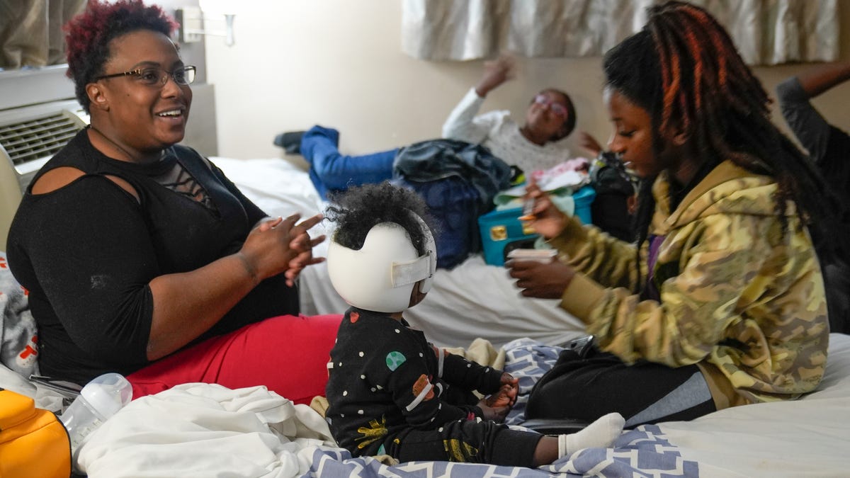 Johnika Jamison, left, with her three daughters Eden, 15 Eastin , 9 and Everly, 1, and her husband Tristian Harris, back right, in the small hotel room they call home. Jamison married Harris, Everly's father, in December 2024. The family has been homeless for more than a year after Jamison and her husband experienced medical troubles that put them out of work.