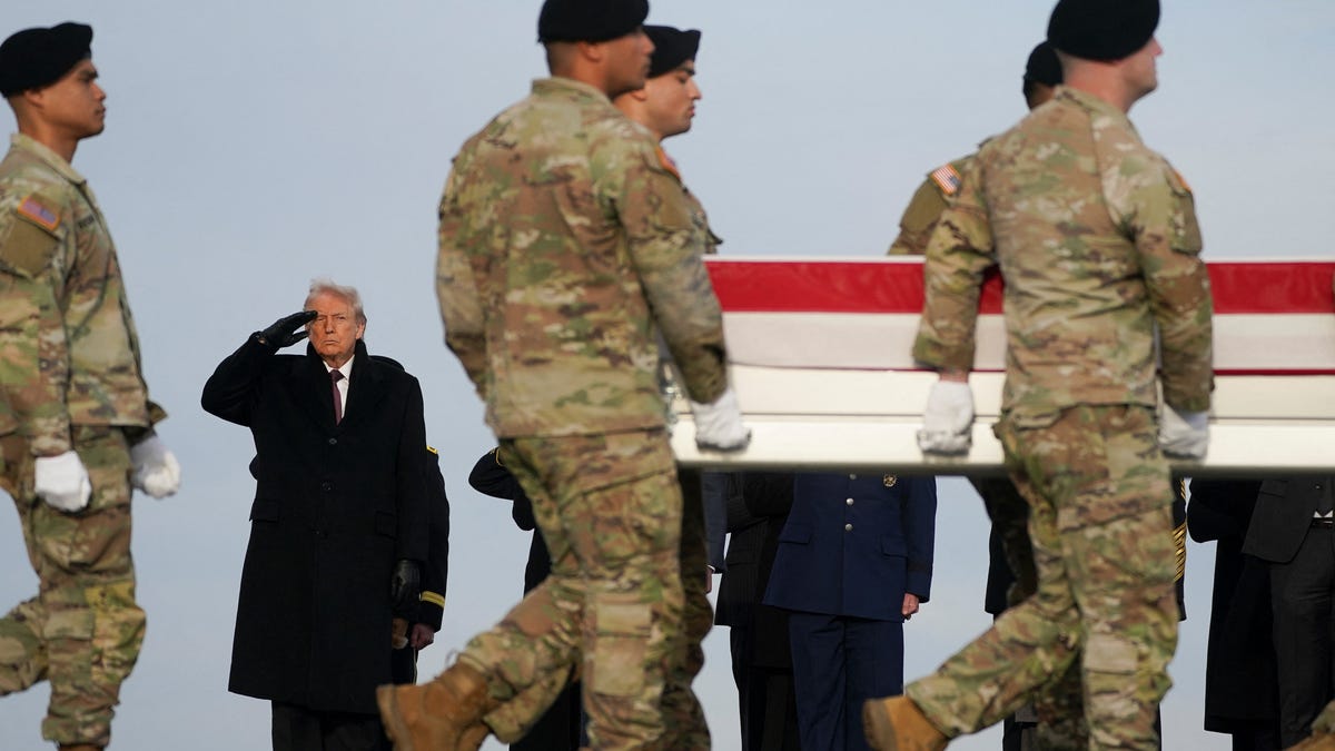 President Donald Trump salutes as members of the military carry a transfer case, during a dignified transfer of the remains of two Iowa National Guard members killed in Syria, Sgt. Edgar Torres Tovar and Sgt. William Howard, and Ayad Mansoor Sakat, of Macomb, Michigan, who was working as an interpreter in Syria, at Dover Air Force Base in Dover, Delaware, on Dec. 17, 2025.