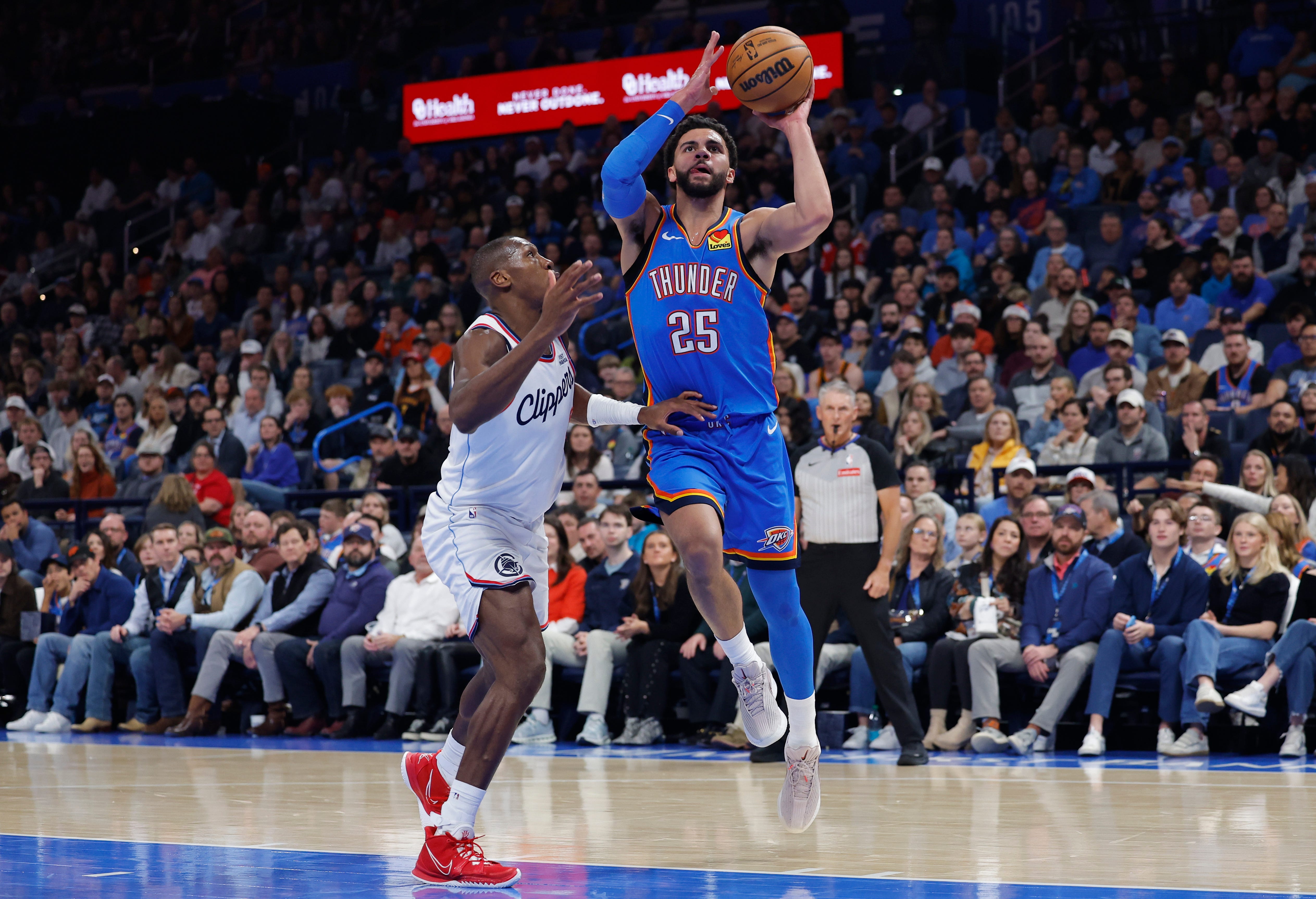 Dec 18, 2025; Oklahoma City, Oklahoma, USA; Oklahoma City Thunder guard Ajay Mitchell (25) drives to the basket beside Los Angeles Clippers guard Kris Dunn (8) during the second quarter at Paycom Center. Mandatory Credit: Alonzo Adams-Imagn Images