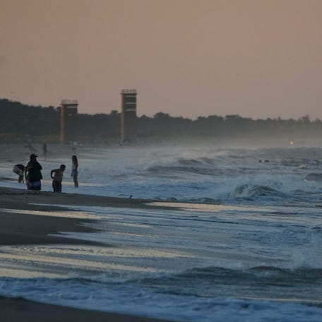 Bathers take in the last moments of daylight in Rehoboth Beach, July 24, 2025.