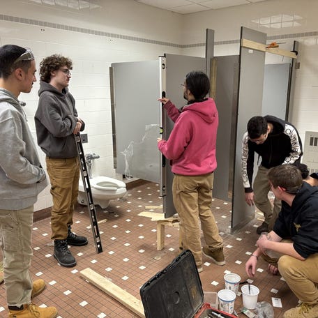 Carpentry students at Worcester Technical High School work on repairing a bathroom at the school.