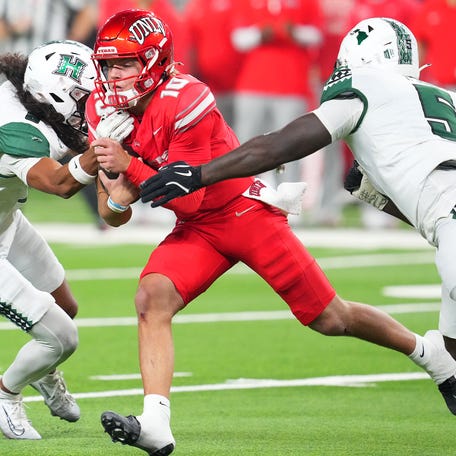 UNLV quarterback Anthony Colandrea (10) runs between Hawaii defensive back Kilinahe Mendiola-Jensen (8) and defensive lineman Tariq Jones (5) during their game at Allegiant Stadium.