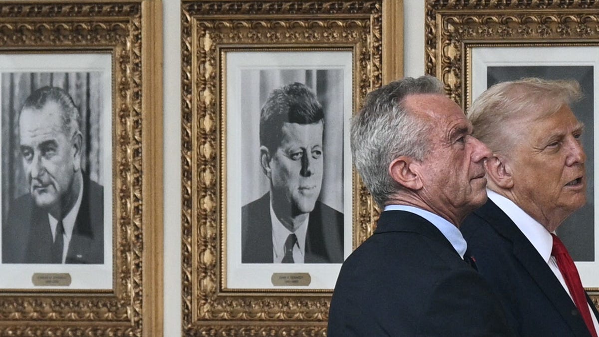 US President Donald Trump and Secretary of Health and Human Services Robert F. Kennedy Jr. walk along the colonnade past photographs of former US Presidents, including Lyndon B. Johnson and John F. Kennedy, as Trump returns to the White House in Washington, DC, on September 30, 2025.