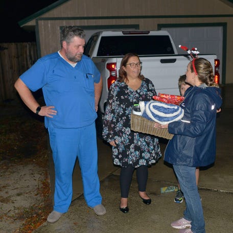 Gulf Power employee Sarah Gatewood surprises the Davis family with gifts and holiday decorations when the Gulf Breeze family arrives home on Monday, Dec. 6, 2021. Gulf Power and Baptist selected Davis to receive the decoration as a health care hero.    Health Care Hero Gulf Power
