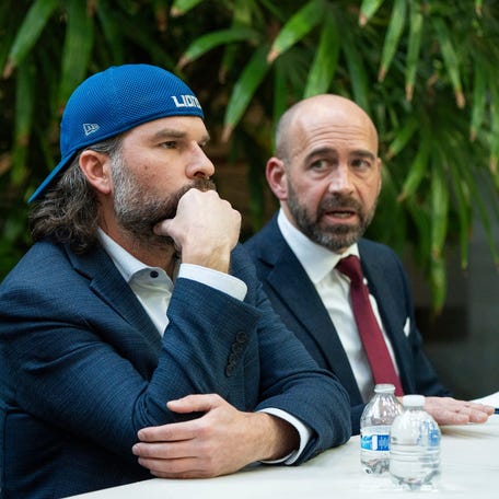 Detroit Lions fan Ryan Kennedy, center, listens during a press conference while being represented by attorneys Sean Murphy, left, and Shawn Head, right, during a press conference at Head Murphy Law in Farmington Hills on Friday, December 26, 2025.