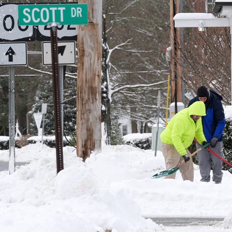 Workers shovel snow along a sidewalk on Route 100 in Somers, New York, on Dec. 27, 2025.