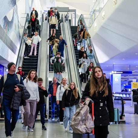 Passengers go down the escalators after arriving to La Guardia Airport on December 23, 2025 in New York.
