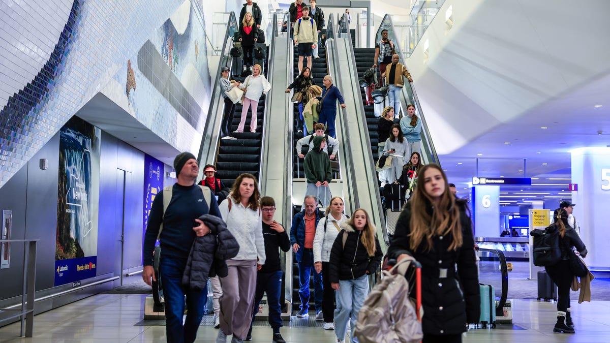 Passengers go down the escalators after arriving to La Guardia Airport on December 23, 2025 in New York.