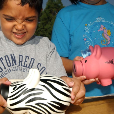 LOS ANGELES - AUGUST 31: Michael Khatchadourina (L), 7, tries to open his piggy bank as he and his sister Krysta, 9, make a donation for victims of Hurricane Katrina at a daylong disaster relief collection event held by The American Red Cross, The Los Angeles Dodgers, The Walt Disney Co. and KABC at Dodger Stadium August 31, 2005 in Los Angeles. Katrina left hundreds feared dead and thousands homeless in Louisiana, Mississippi, Alabama and Florida. (Photo by Ann Johansson/Getty Images)