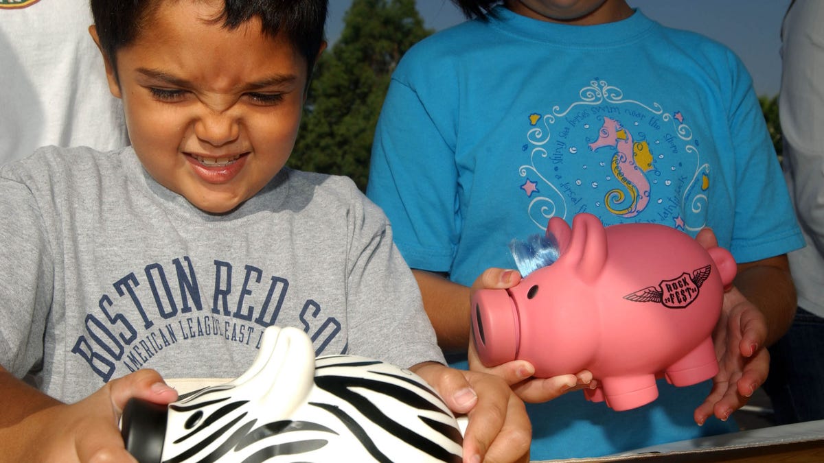 LOS ANGELES - AUGUST 31: Michael Khatchadourina (L), 7, tries to open his piggy bank as he and his sister Krysta, 9, make a donation for victims of Hurricane Katrina at a daylong disaster relief collection event held by The American Red Cross, The Los Angeles Dodgers, The Walt Disney Co. and KABC at Dodger Stadium August 31, 2005 in Los Angeles. Katrina left hundreds feared dead and thousands homeless in Louisiana, Mississippi, Alabama and Florida. (Photo by Ann Johansson/Getty Images)