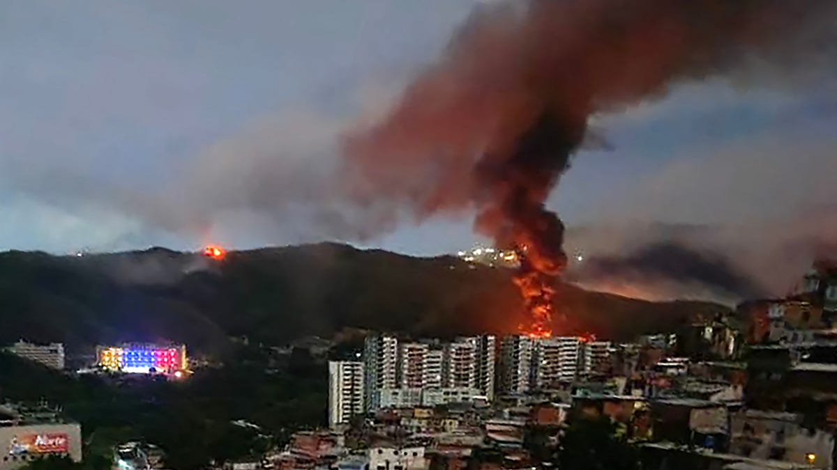 Fire at Fuerte Tiuna, Venezuela's largest military complex, is seen from a distance after a series of explosions in Caracas on January 3, 2026.