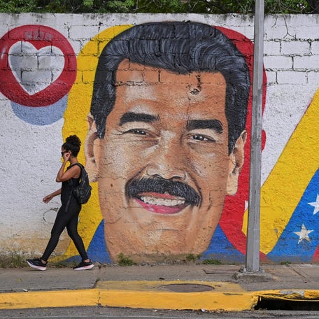 A woman walks past a mural of Venezuela's President Nicolas Maduro in Caracas, Venezuela, on November 24, 2025.