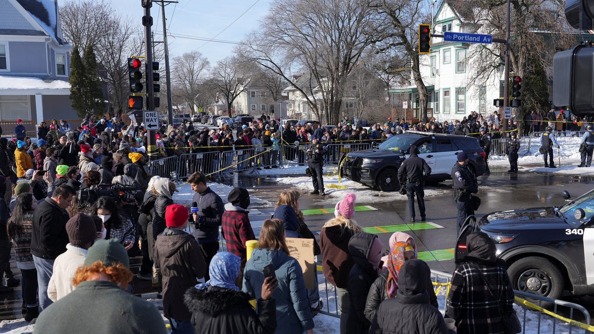 Members of the community gather as police officers block the scene after the driver of a vehicle was shot, in Minneapolis, Minnesota, U.S., Jan. 7, 2026.