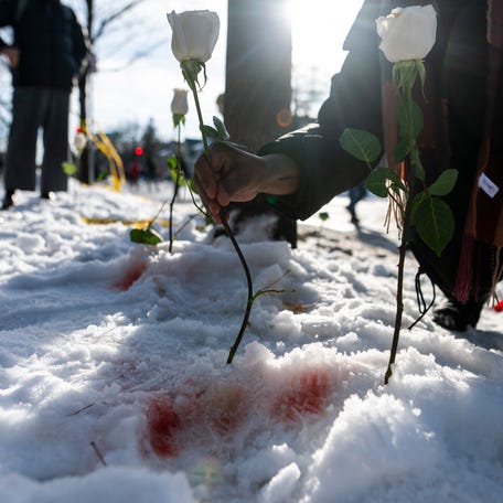 A person places a flower at the site where a woman was reportedly shot and killed by an ICE agent during federal law enforcement operations on Jan. 7, 2026 in Minneapolis, Minn. According to federal officials, the agent, "fearing for his life" killed a woman during a confrontation in south Minneapolis.