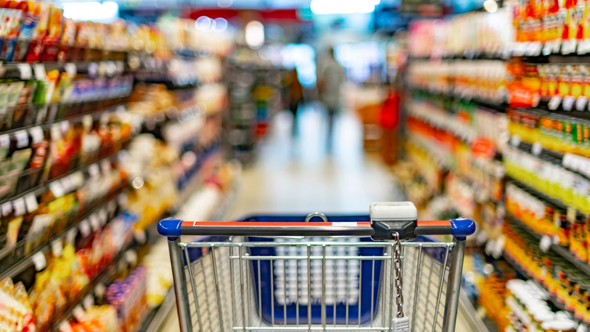 A shopping cart by a store shelf in a supermarket