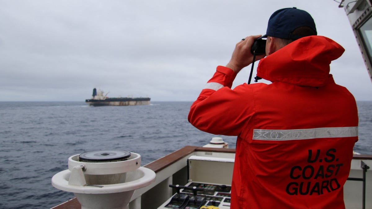 A U.S. Coast Guard official looks through binoculars at the ship Marinera, formerly called the Bella 1, in this handout image released January 7, 2026.