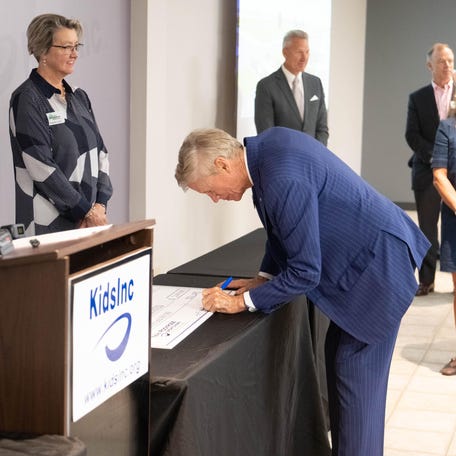 Richard Ware chairman of Amarillo National Banks signs a donation check as a member of the of the Engler Foundation July 28 at Kid's Inc corporate headquarters In Amarillo.