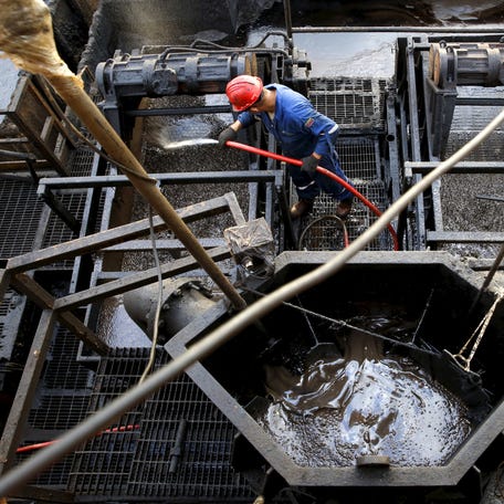 The flow of drilling mud is seen in a container while an oilfield worker works on a drilling rig at an oil well operated by Venezuela's state oil company PDVSA, in the oil rich Orinoco belt, near Cabrutica at the state of Anzoategui April 16, 2015. Venezuela has launched talks this month on a novel plan to blend the country's heavy crude with light oil from other OPEC allies, seeking to create a new variety that can compete against   swelling U.S. and Canadian supplies. The proposal, which would expand on a pilot scheme involving Algerian oil last year, envisions supplying refineries built for medium-grade crudes rather than the light oil that has become plentiful as a result of the North American shale boom, said the head of state oil company PDVSA, Eulogio del Pino. Picture taken on April 16, 2015. REUTERS/Carlos Garcia Rawlins