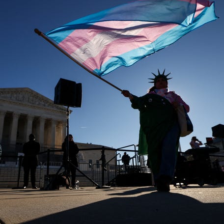 A demonstrator waves a transgender flag outside the U.S. Supreme Court as justices hear oral arguments in two cases over Republican-backed state laws banning transgender athletes from female sports teams at public schools, in Washington, D.C., Jan. 13, 2026.