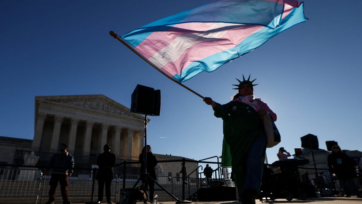 A demonstrator waves a transgender flag outside the U.S. Supreme Court as justices hear oral arguments in two cases over Republican-backed state laws banning transgender athletes from female sports teams at public schools, in Washington, D.C., Jan. 13, 2026.
