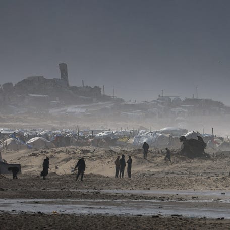 Palestinians gather near tents sheltering displaced people, amid a windstorm, in Gaza City, on Jan, 13, 2026.
