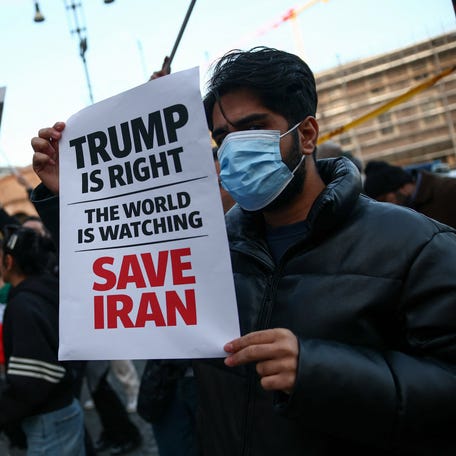 A man shows a sign mentioning U.S. President Donald Trump during a rally in support of nationwide protests in Iran, in Rome, Italy, on Jan. 13, 2026.